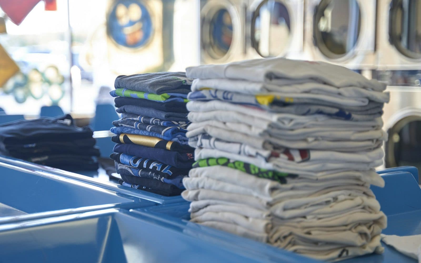 Stacks of freshly folded laundry on a folding table in a laundromat